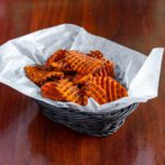 A paper-lined basket of sweet potato waffle fries